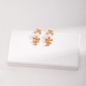 Geometric gold earrings with pearl centre and architectural flow. Be the gliding grace.