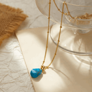 Gold pendant with turquoise bead on linen, minimal and calming jewelry. Be the Gliding Grace.