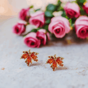 Maple leaf-shaped red crystal stud earrings with gold-tone finish. Be the gliding grace.